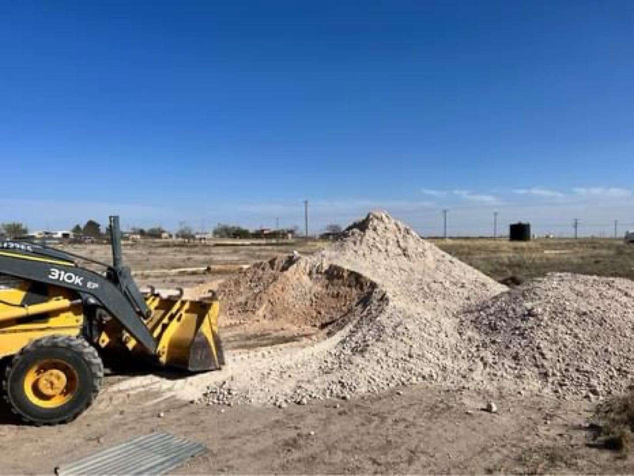 Backhoe beside gravel piles